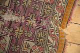 Exposed foundation on antique Caucasian rug detail, showing aubergine, silver, and tangerine patterns.