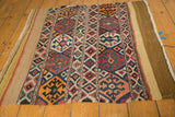 Shahsavan Kilim fragment's geometric pattern in tangerine, navy, and red, bordering the banded plain weave.