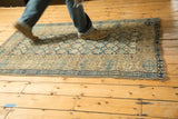 Detail of antique Caucasian rug's geometric patterns in blues and beige, with foundation showing.