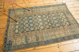 Antique Caucasian rug's geometric indigo border, tattered end, and pile wear with foundation showing.