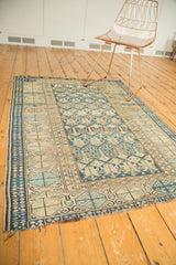 Tattered end, geometric buds, and wear on an Antique Caucasian rug in indigo and sky blue.