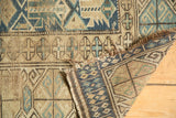 Antique Caucasian rug with geometric stylized plant motifs, hand-knotted reverse, and worn edge.