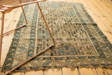 Antique Caucasian rug's tattered bottom edge, featuring beige, sky blue, and brown geometric patterns.