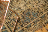 Tattered edge of an antique Caucasian rug, with stepped geometric ivory and sky blue motifs.