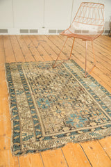 Tattered corner of an Antique Caucasian rug, displaying geometric sky blue and beige patterns.