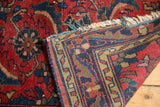Folded vintage Dargezine rug showcasing rich red herati field, detailed border, and tattered fringe.