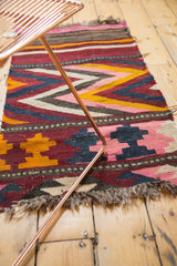 Vintage Kilim rug: diamond chevron in burgundy, pink, yellow, and blue with tattered fringe.