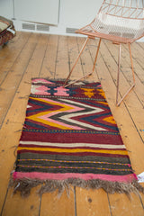 Tattered brown fringe and pink, charcoal, yellow banded stripes on vintage Kilim.