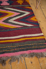Tattered fringe and woven stripes in pink, red, yellow, charcoal on a vintage Kilim.