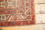 Localized wear and exposed foundation on a vintage Malayer rug runner corner.