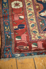 Antique Kurdish rug detail: red field with floral sections and blue border with primitive arabesques.