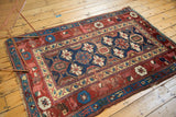 Aged corner of an antique Kurdish rug with indigo, red Mina Khani patterns, and visible foundation.