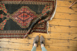 Antique Senneh rug's scalloped red medallion, intricate boteh border, and dark charcoal field.