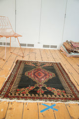 Senneh rug corner, dark field, red scalloped medallion, boteh border, and worn fringe.