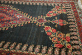 Intricate madder red florals, gold accents, and boteh border on the worn dark field.