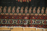 Antique Senneh rug border detailing charcoal boteh, madder red floral motifs, and hard tattered fringe.