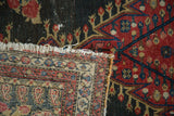 Antique Senneh rug detail: fine back weave, worn fringe, and botanical motifs on dark pile.