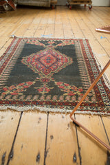 Dark field of antique Senneh rug showing red floral bouquets, boteh border, and tattered fringe.