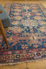 Antique Soumac rug detail: geometric finned medallions, starbursts, navy field, and rich textural patina.