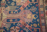 Antique Soumac rug detail: geometric finned motifs in navy, aubergine, gold, with textured wear.