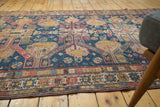 Antique Caucasus Soumac rug, geometric patterns in navy, red, gold, with aged texture.