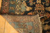 Folded antique Malayer rug corner, showing full pile, hand-knotted foundation, and tattered fringe.