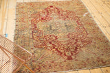 Antique Kaisary rug's wine red floral field, beige border, visible tatter, and central hole.