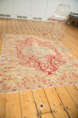 Close view of tattered edge, worn beige and red floral patterns on the antique Kaisary rug.