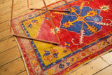 Vintage Oushak rug corner showing red field, yellow border, and blue serrated floral motif.