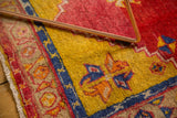 Stylized blue and orange tendrils on a saffron yellow field of a vintage Oushak rug.