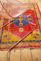Vintage Oushak rug corner with red, yellow, blue floral pattern and tattered fringe.