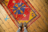 Vintage Oushak rug with a striking blue medallion, vibrant cherry red field, and visible even wear.