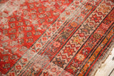 Antique Malayer runner's tomato red field and starburst border, showing storied wear.