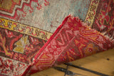 Antique Mudjur rug corner folded, showing faded blue-red pile and intricate red woven foundation.