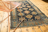 Lower corner of antique Malayer runner, dark blue field, geometric medallions, tattered fringe.