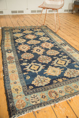 Antique Malayer rug corner: tattered fringe, geometric light blue border, field motifs.