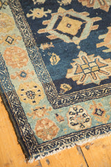 Antique Malayer runner corner with indigo field, gold patterns, pale blue border, and tattered fringe.