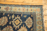 Antique Malayer runner corner: indigo field, dusty gold motifs, light blue-green border, tattered edge.