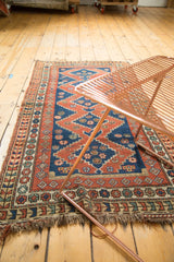 Vintage Caucasian rug corner detail, madder red and indigo geometric patterns, multi-layered border, worn fringe.