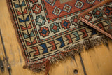 Caucasian rug corner, madder red, indigo blue, ivory, oxidized green geometric design, tattered fringe.