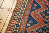 Vintage Caucasian rug detail showing geometric border with madder red, indigo, ivory, and edge tatter.