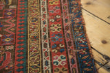 Tattered side edge of an antique Karabagh runner, featuring colorful Herati patterns.