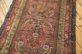 Detailed view of antique Karabagh runner's multi-banded border and colorful Herati pattern, showing edge wear.