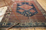 Antique Afshar rug's intricate lower border showing pinwheel florals, animal motifs, and rich navy, red, ivory tones.