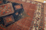 Pomegranate red dotted field, ivory tribal border, and worn fringe of an Antique Afshar rug.