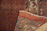 Antique Afshar rug: hand-knotted foundation, frayed edge, worn pomegranate red pile with blue motifs.