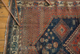 Antique Afshar rug with rich pomegranate red field, navy diamond motif, and aged texture.