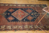 Worn corner of an antique Afshar rug, showing tattered edge and intricate floral border.