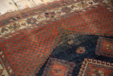 Worn navy blue section of antique Afshar rug featuring pomegranate red motifs and dotted field.