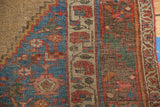Antique Bijar rug border detail, featuring serrated tribal motifs in camel, blue, red, green.